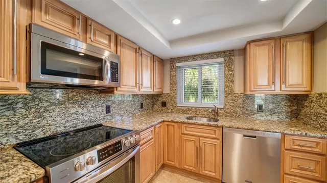 a kitchen with granite countertop a sink stainless steel appliances a window and cabinets