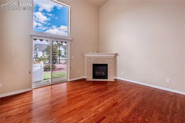 an empty room with wooden floor and a ceiling fan