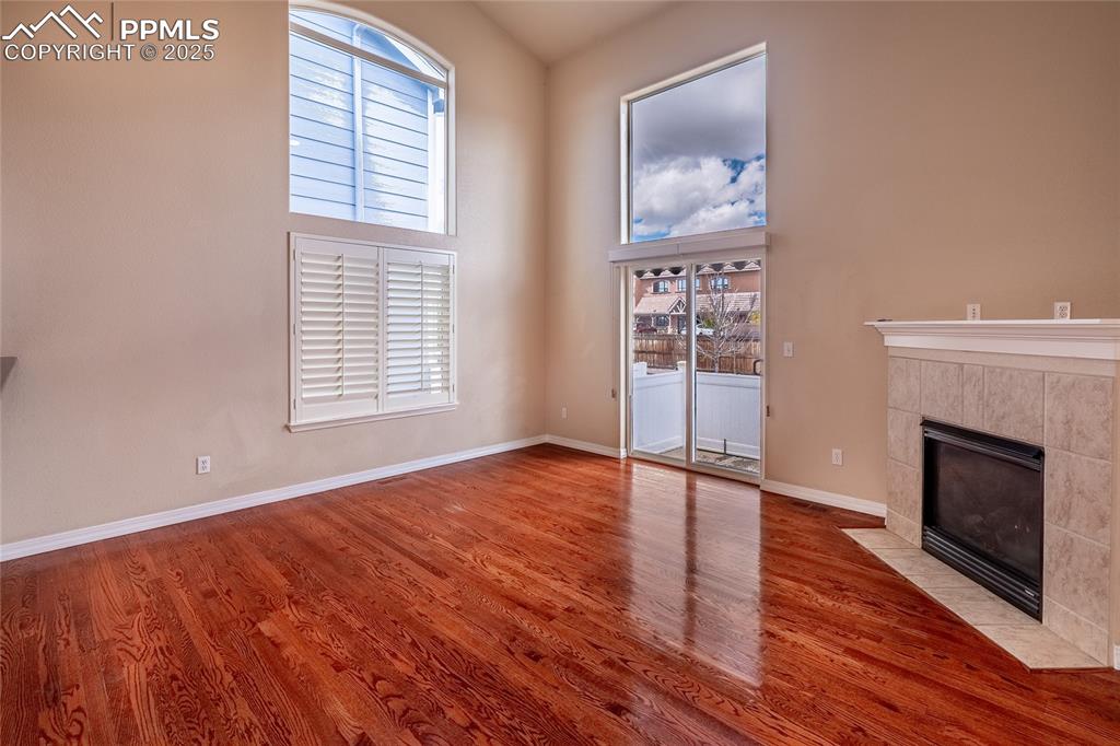 7313 Owings Point Peyton, CO 80831 - Photo 12 of 47 Unfurnished living room featuring a high ceiling, a tiled fireplace, and wood finished floors