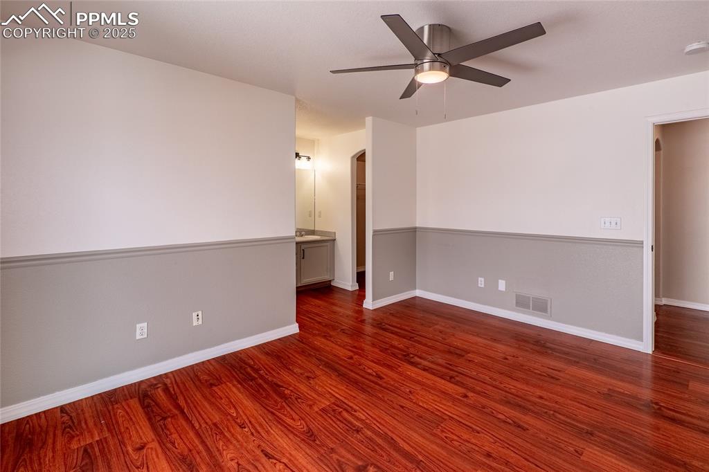 7313 Owings Point Peyton, CO 80831 - Photo 15 of 47 Spare room with arched walkways, dark wood-style flooring, and ceiling fan