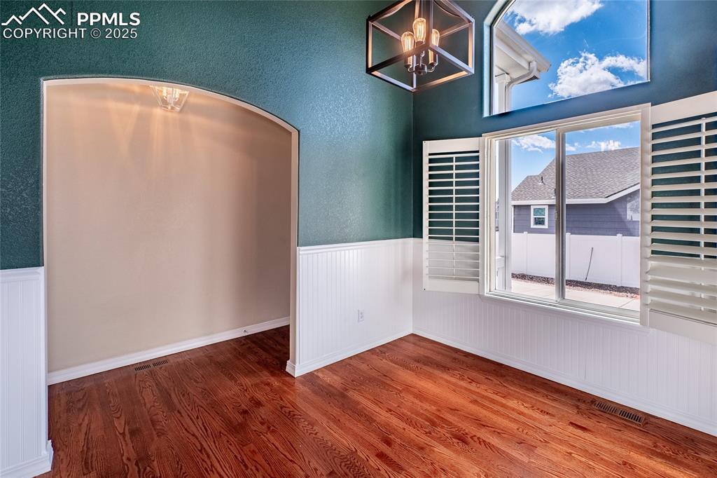 7313 Owings Point Peyton, CO 80831 - Photo 5 of 47 Unfurnished dining area with wood finished floors, a chandelier, wainscoting, and arched walkways