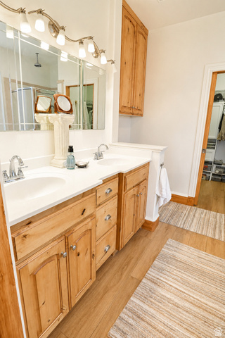 1055 North 1000 East Mapleton, UT 84664 - Photo 15 of 112 Bathroom vanity featuring dual undermount sinks, white countertops, natural wood cabinetry, brushed nickel hardware, and wood-finish flooring