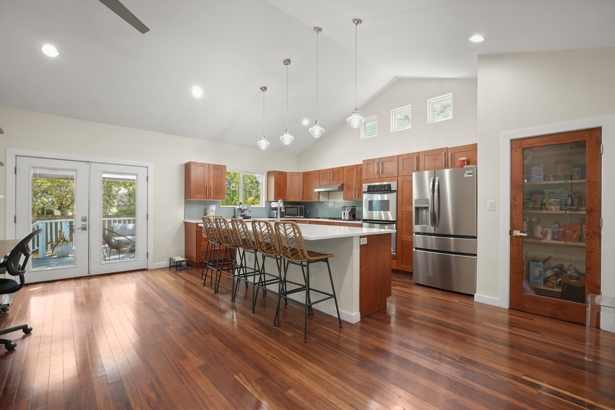 2501 Del Curto Road Austin, TX 78704 - Photo 8 of 26 Rich hardwood flooring complements a spacious open kitchen featuring vaulted ceilings and a glass-paneled pantry.