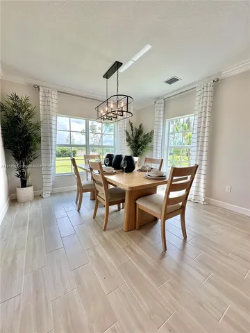 a dining room with wooden floor a chandelier a wooden table and chairs