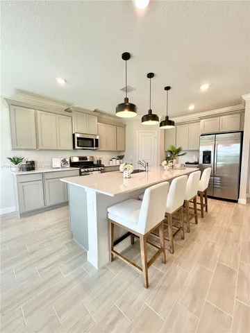 a kitchen with stainless steel appliances kitchen island granite countertop a sink dishwasher a stove a microwave oven and a dining table with wooden floor