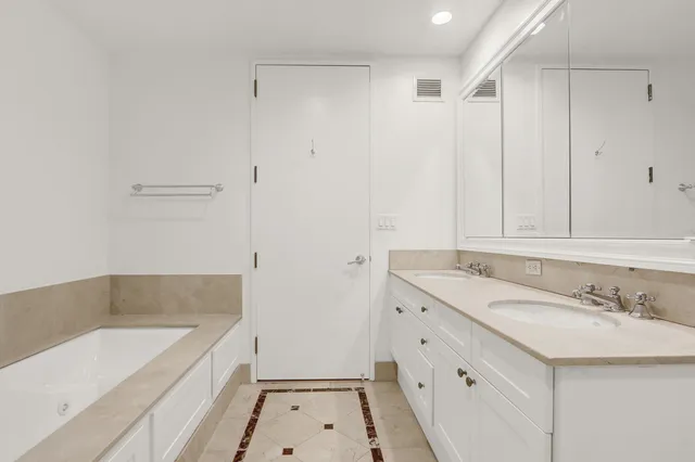 a bathroom with a sink double vanity granite tub and a mirror