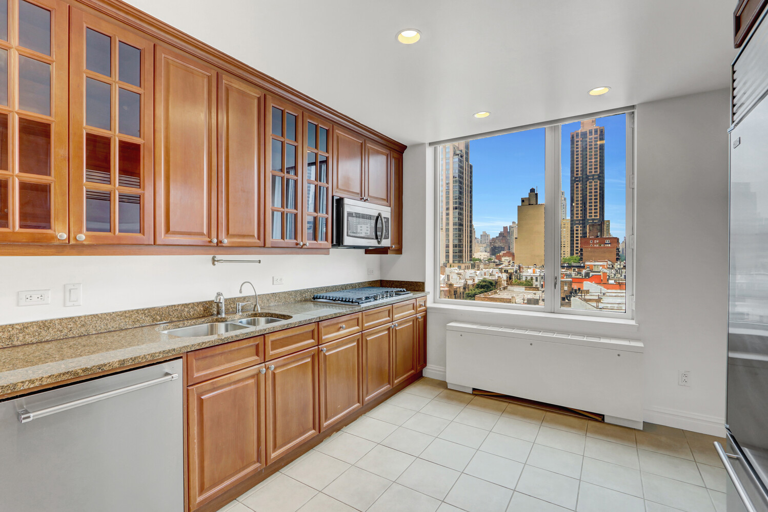 90 East End Avenue, Unit 10B Manhattan, NY 10028 - Photo 34 of 39 a large kitchen with stainless steel appliances granite countertop a sink and dishwasher next to a window