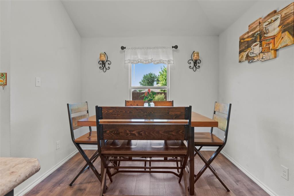 409 Wilson Way Denton, TX 76207 - Photo 13 of 33 Dining area featuring wood-finish flooring, a window with natural light, and decorative wall sconces