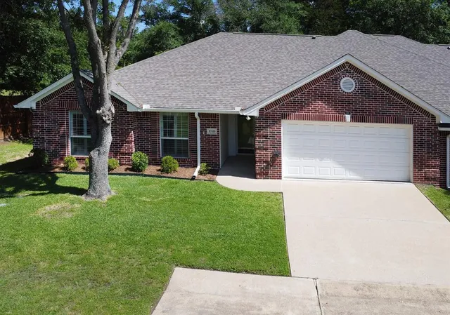 a front view of a house with a garden and trees
