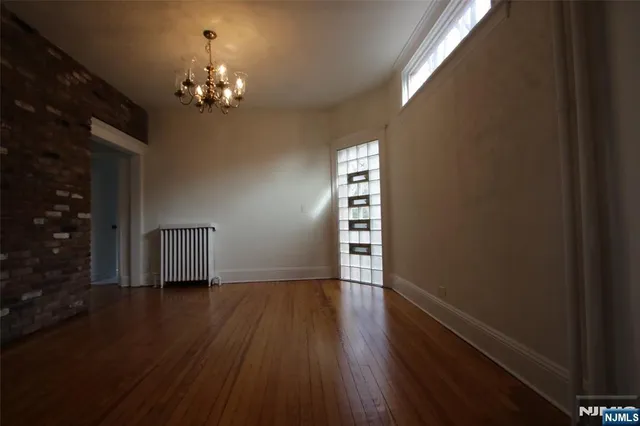 a view of empty room with wooden floor and window