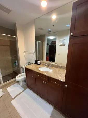 a spacious bathroom with a granite countertop sink a toilet a mirror and shower