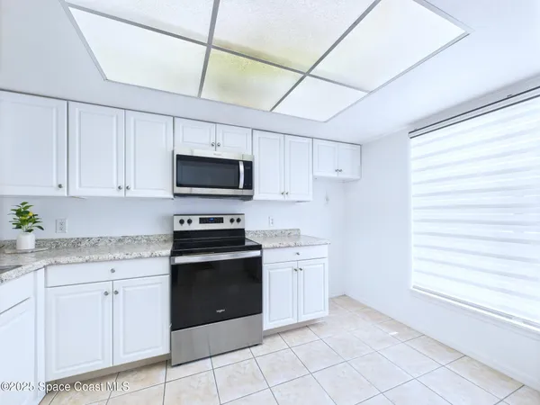 a kitchen with granite countertop white cabinets stainless steel appliances and a window