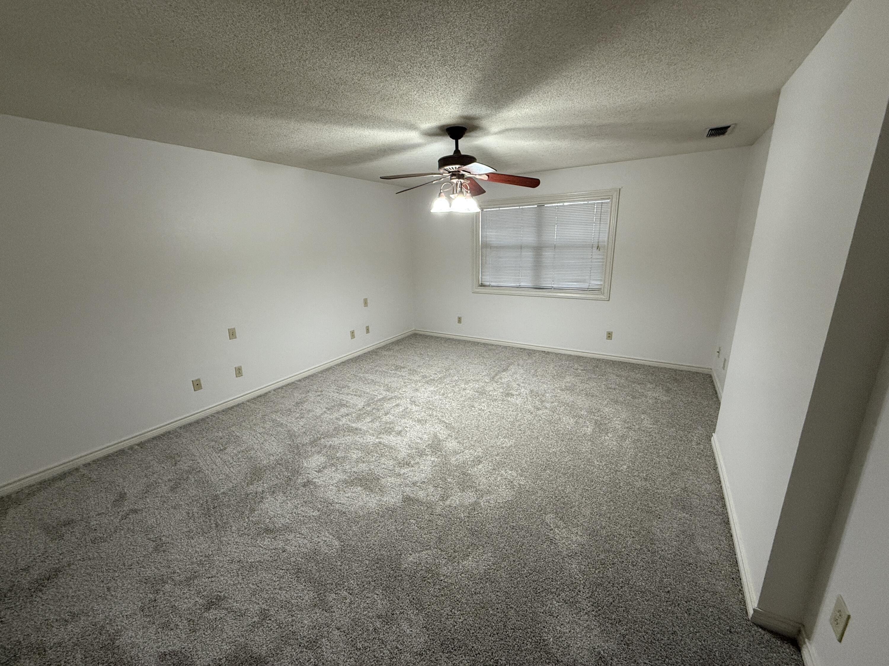 4828 11th Street Lubbock, TX 79416 - Photo 5 of 12 an empty room with a ceiling fan and carpet