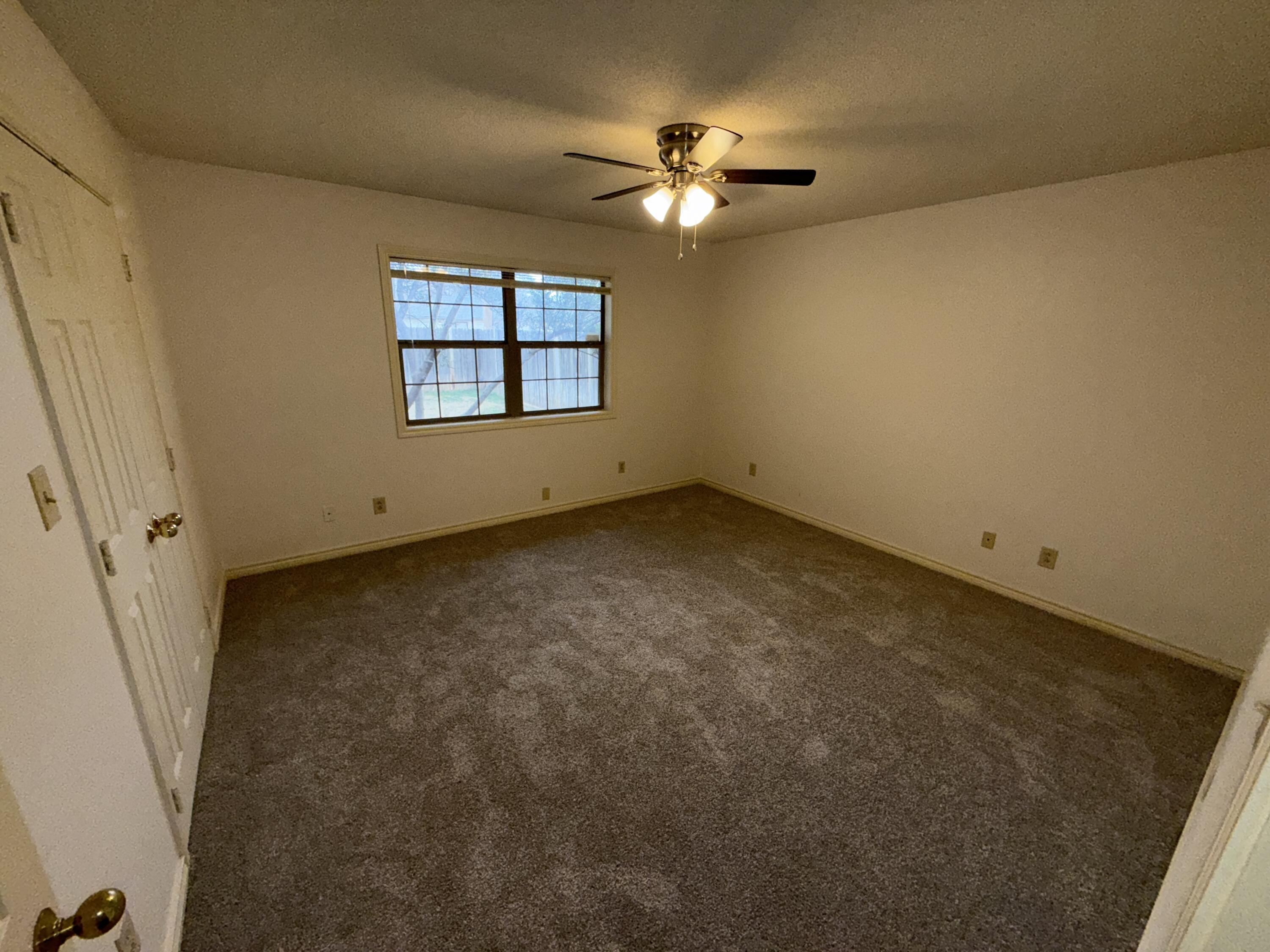 4828 11th Street Lubbock, TX 79416 - Photo 6 of 12 an empty room with windows and chandelier fan