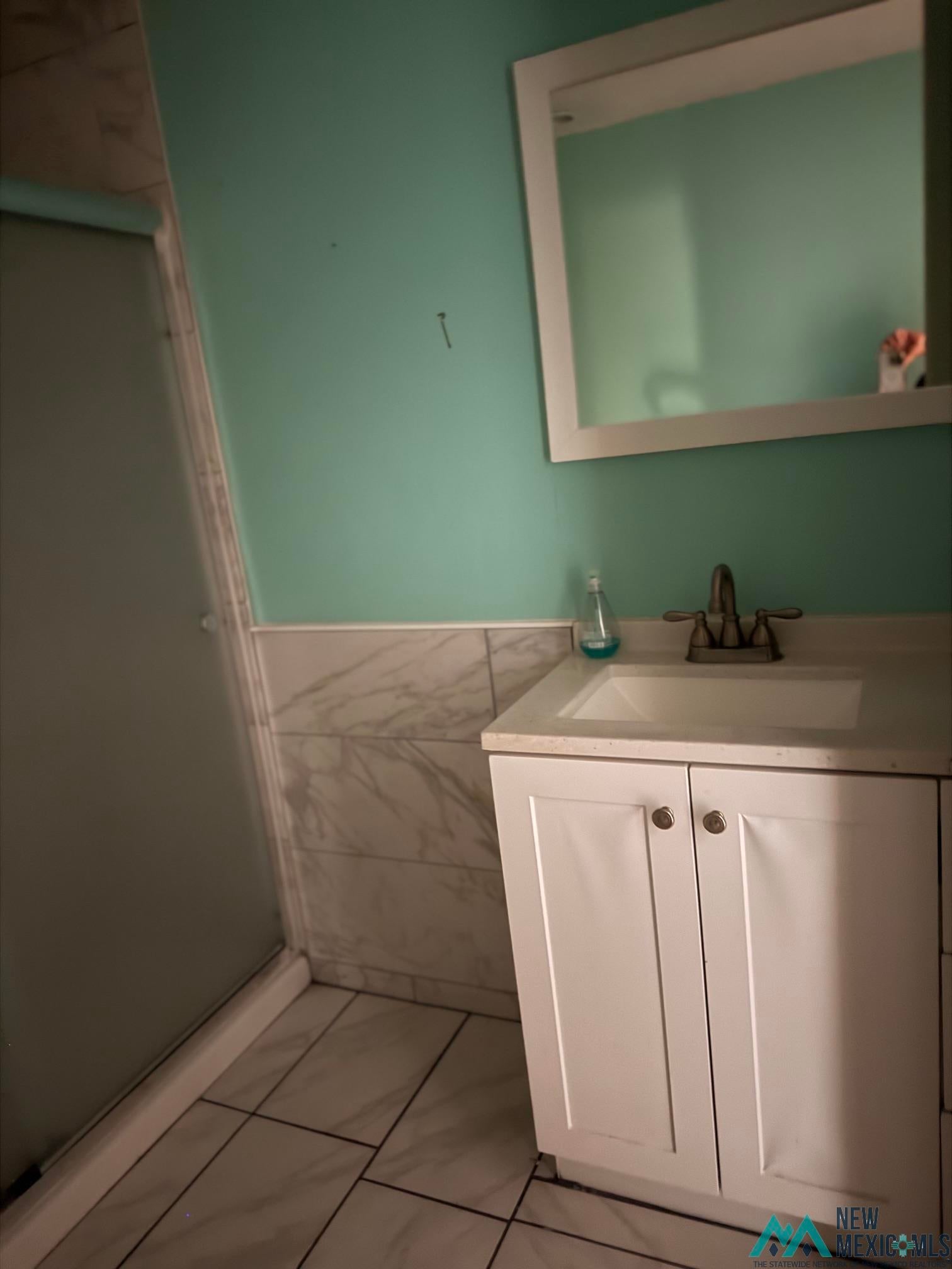 104 Shawnee Road Logan, NM 88426 - Photo 29 of 36 Bathroom featuring a single-sink vanity with white cabinetry, a light-colored countertop, and a framed mirror