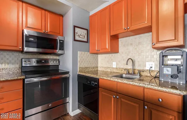 a kitchen with granite countertop a sink stove and microwave