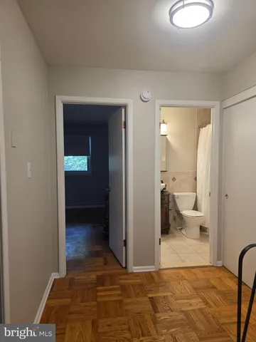a view of a hallway with wooden floor and a bathroom