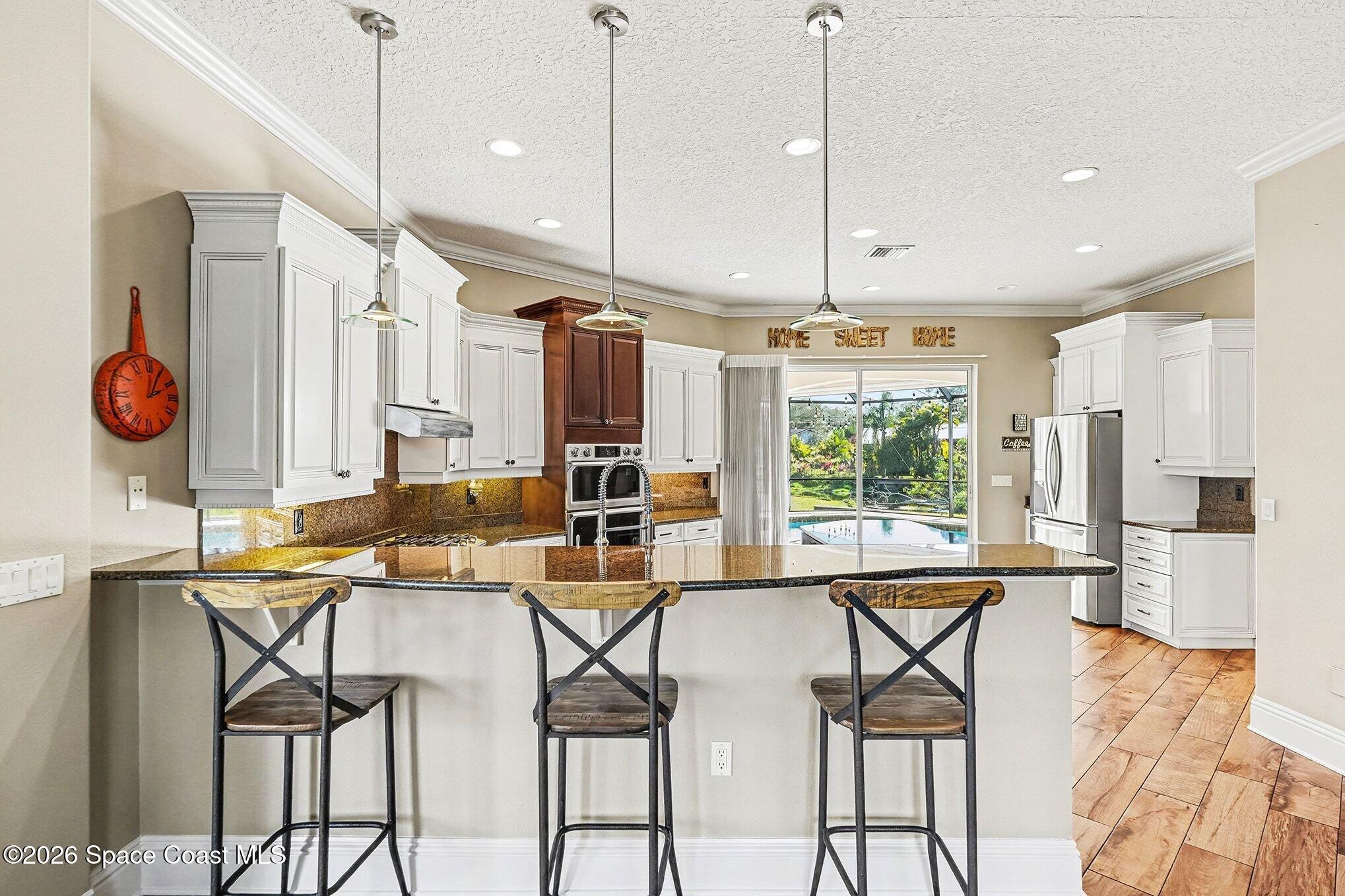 1 Point View Place Cocoa, FL 32926 - Photo 10 of 45 a kitchen with stainless steel appliances kitchen island granite countertop a table chairs and a refrigerator