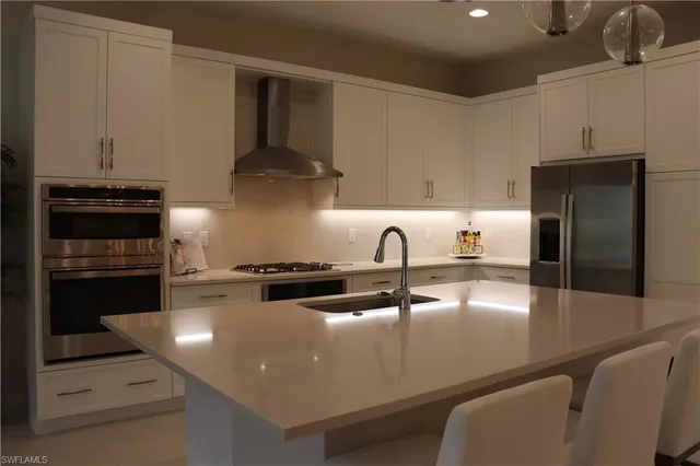 a kitchen with stainless steel appliances granite countertop a sink a stove and a refrigerator