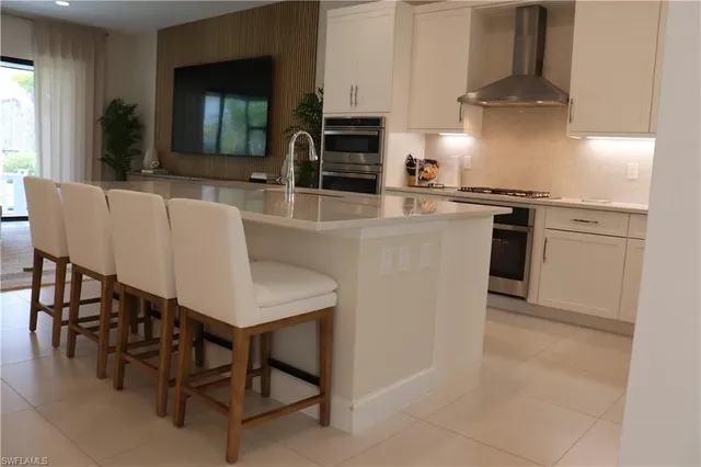 a kitchen with stainless steel appliances granite countertop a stove top oven a sink a dining table and chairs