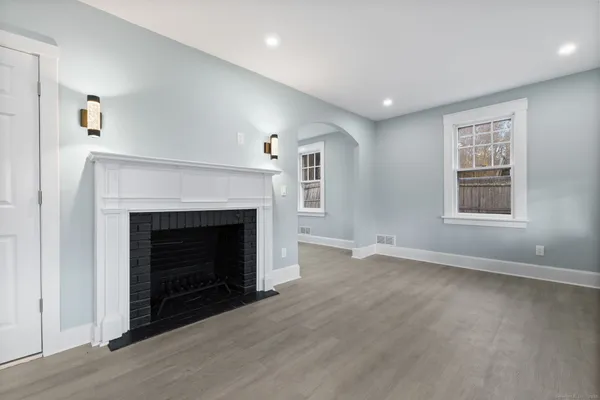 a view of an empty room with wooden floor fireplace and a window