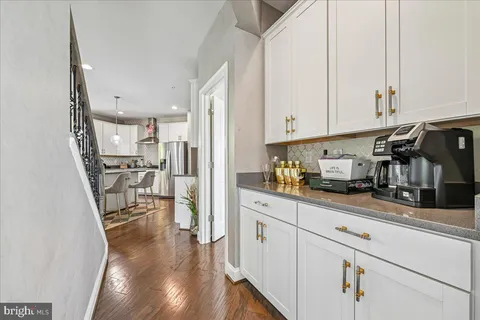 a kitchen with stainless steel appliances granite countertop a stove top oven a sink a dining table and chairs with white cabinets