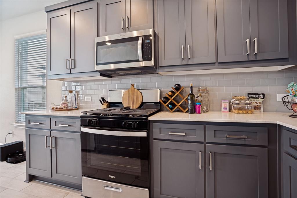 3115 Giovanni Point Princeton, TX 75407 - Photo 6 of 26 Contemporary kitchen featuring gray shaker-style cabinetry, stainless steel appliances, a subway tile backsplash, light-toned countertops, and a built-in microwave