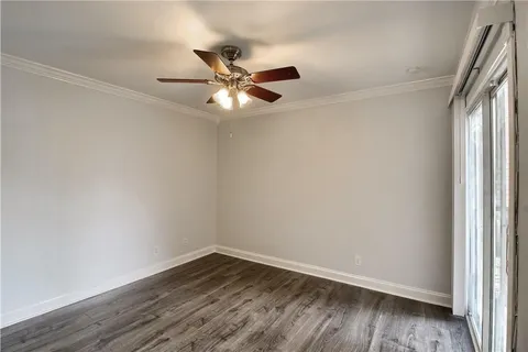 an empty room with wooden floor fan and windows
