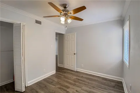 an empty room with wooden floor and ceiling fan
