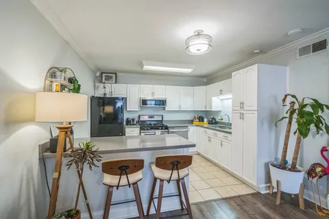 a kitchen with stainless steel appliances granite countertop a refrigerator a stove a sink dishwasher and a dining table with wooden floor