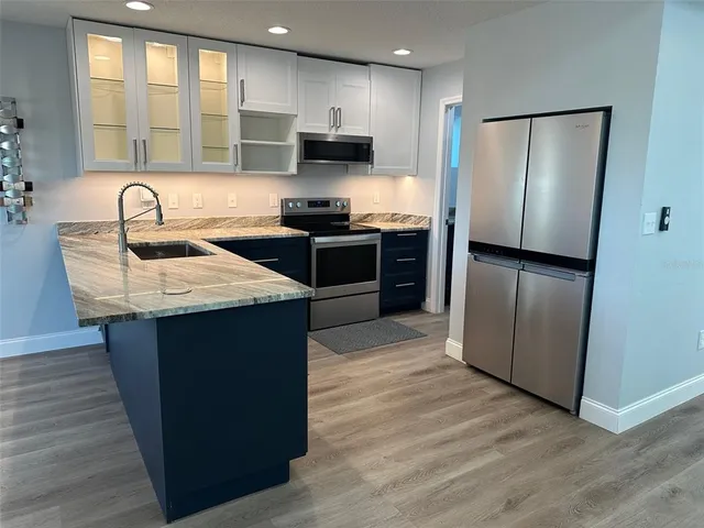 a kitchen with granite countertop a refrigerator and a stove top oven