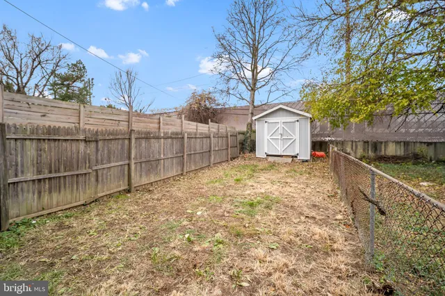 a view of a white house with a large tree and wooden fence