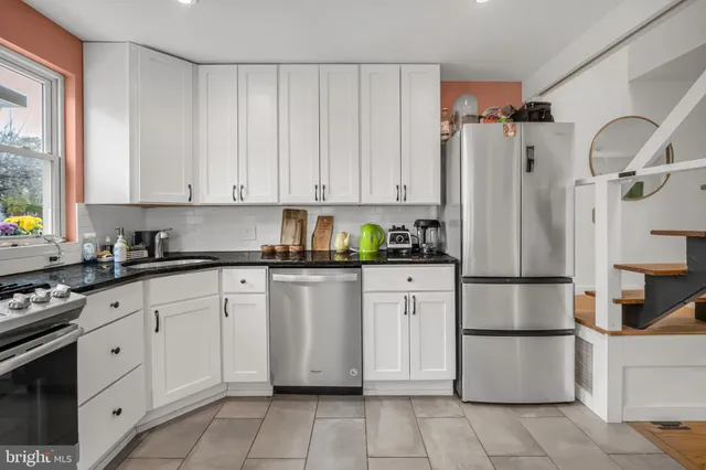 a kitchen with stainless steel appliances granite countertop a refrigerator sink and white cabinets