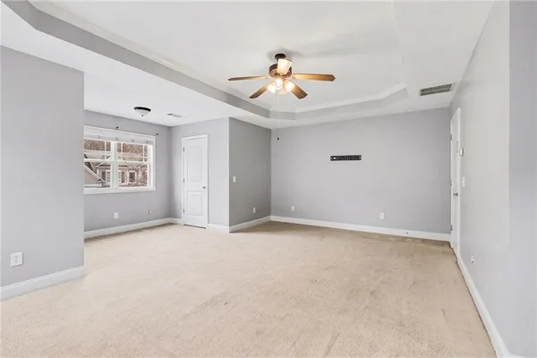 an empty room with windows and ceiling fan