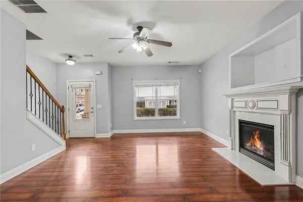a view of an empty room with wooden floor fireplace and a window