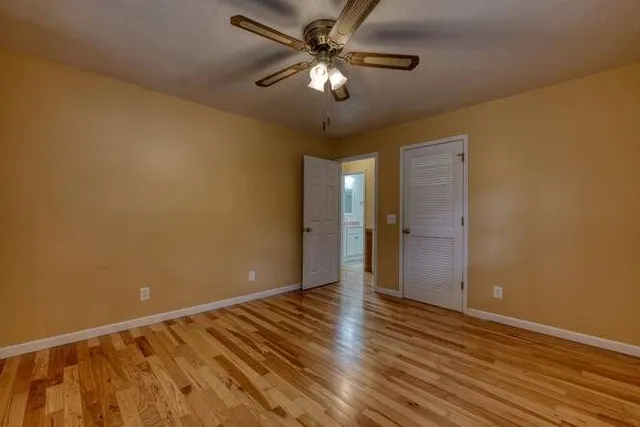 an empty room with wooden floor chandelier fan and closet area