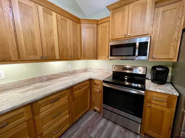 a kitchen with granite countertop cabinets stainless steel appliances and a counter space