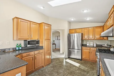 a kitchen with stainless steel appliances granite countertop a refrigerator stove top oven and sink