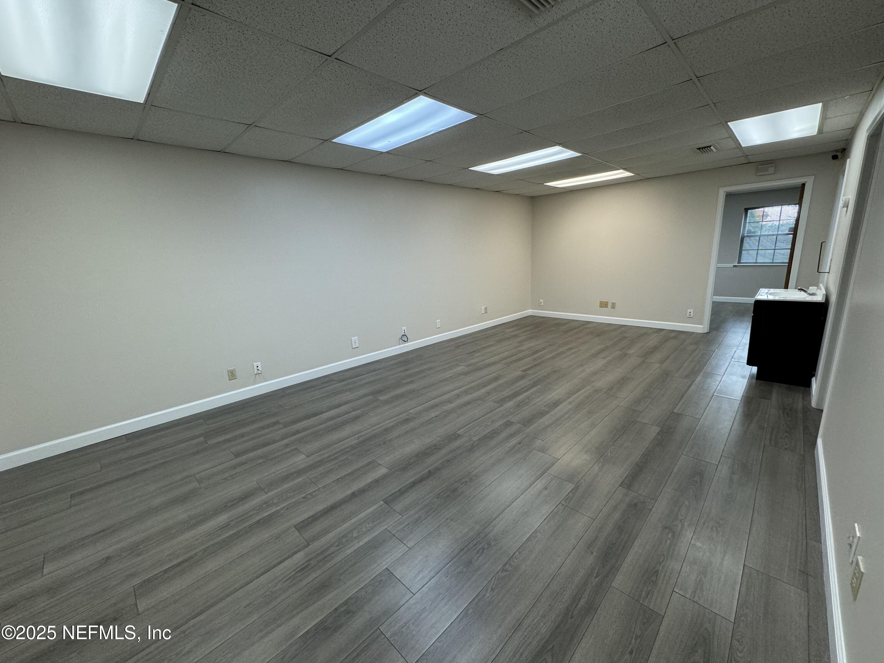 3938 Sunbeam Road Jacksonville, FL 32257 - Photo 11 of 28 an empty room with wooden floor and windows