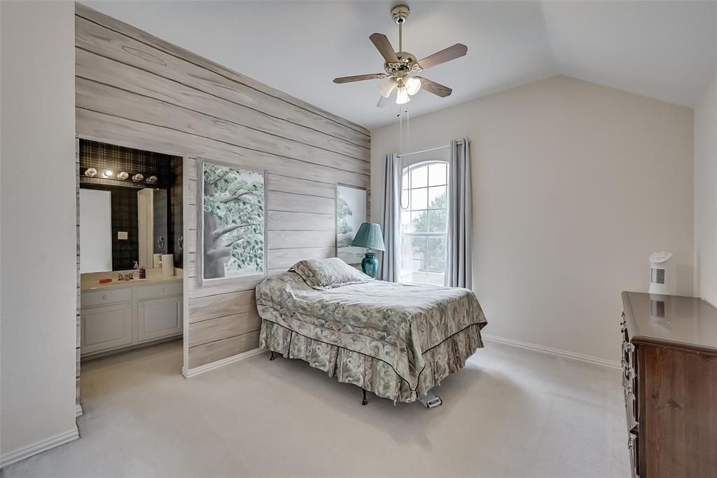 5701 Christy Lane Haltom City, TX 76137 - Photo 11 of 15 Bedroom featuring wood walls, light colored carpet, a ceiling fan, multiple windows, and ensuite bath