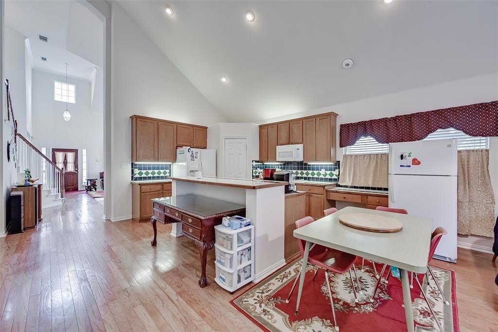 5701 Christy Lane Haltom City, TX 76137 - Photo 3 of 15 Kitchen with white appliances, decorative backsplash, light wood-type flooring, and high vaulted ceiling