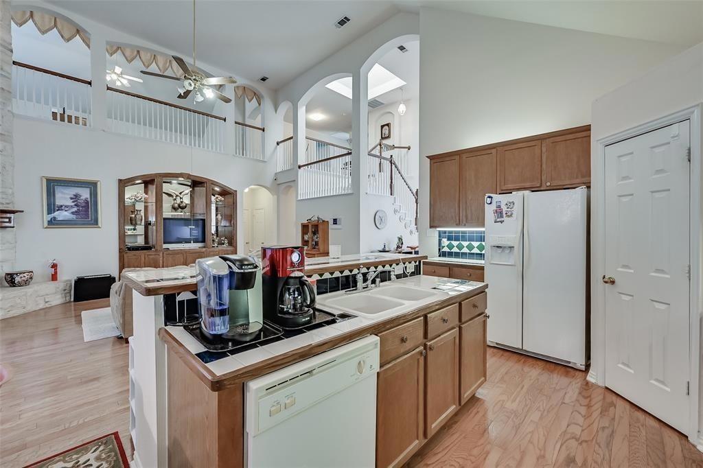 5701 Christy Lane Haltom City, TX 76137 - Photo 7 of 15 Kitchen featuring high vaulted ceiling, arched walkways, white appliances, light wood finished floors, and a kitchen island