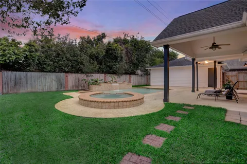 a view of a backyard with table and chairs potted plants and large tree