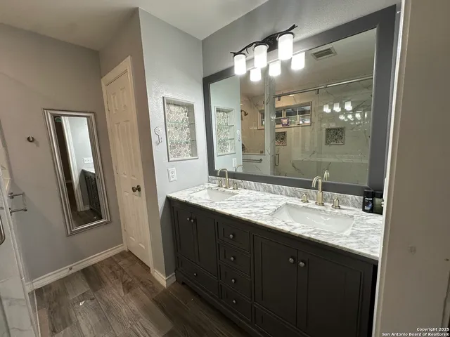 a bathroom with a granite countertop sink a large mirror and a shower