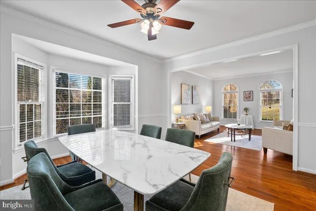 a kitchen with stainless steel appliances granite countertop a stove a sink a microwave a dining table and chairs with wooden floor