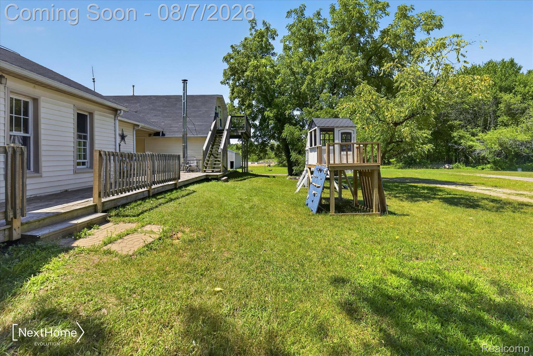23740 Carleton West Road Belleville, MI 48111 - Photo 50 of 58 Expansive grassy yard area featuring a multi-level wooden deck with balusters, a separate elevated wooden play structure, mature trees, and a gravel pathway