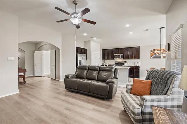 a kitchen with a stove a sink a kitchen island with chairs and wooden floor