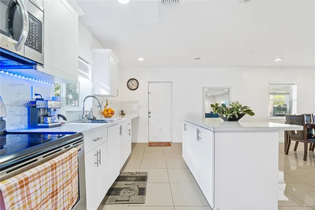 a kitchen with stainless steel appliances a white cabinets and wooden floor
