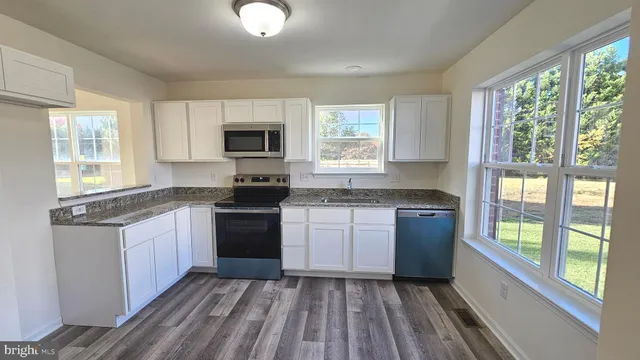 a kitchen with granite countertop a stove a sink and a microwave