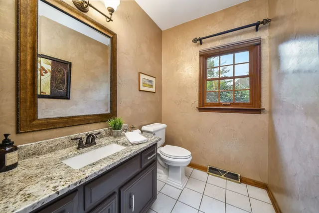 a bathroom with a granite countertop sink a toilet and mirror